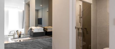 A modern bathroom with a glass-enclosed shower, a marble sink, and neatly folded towels.