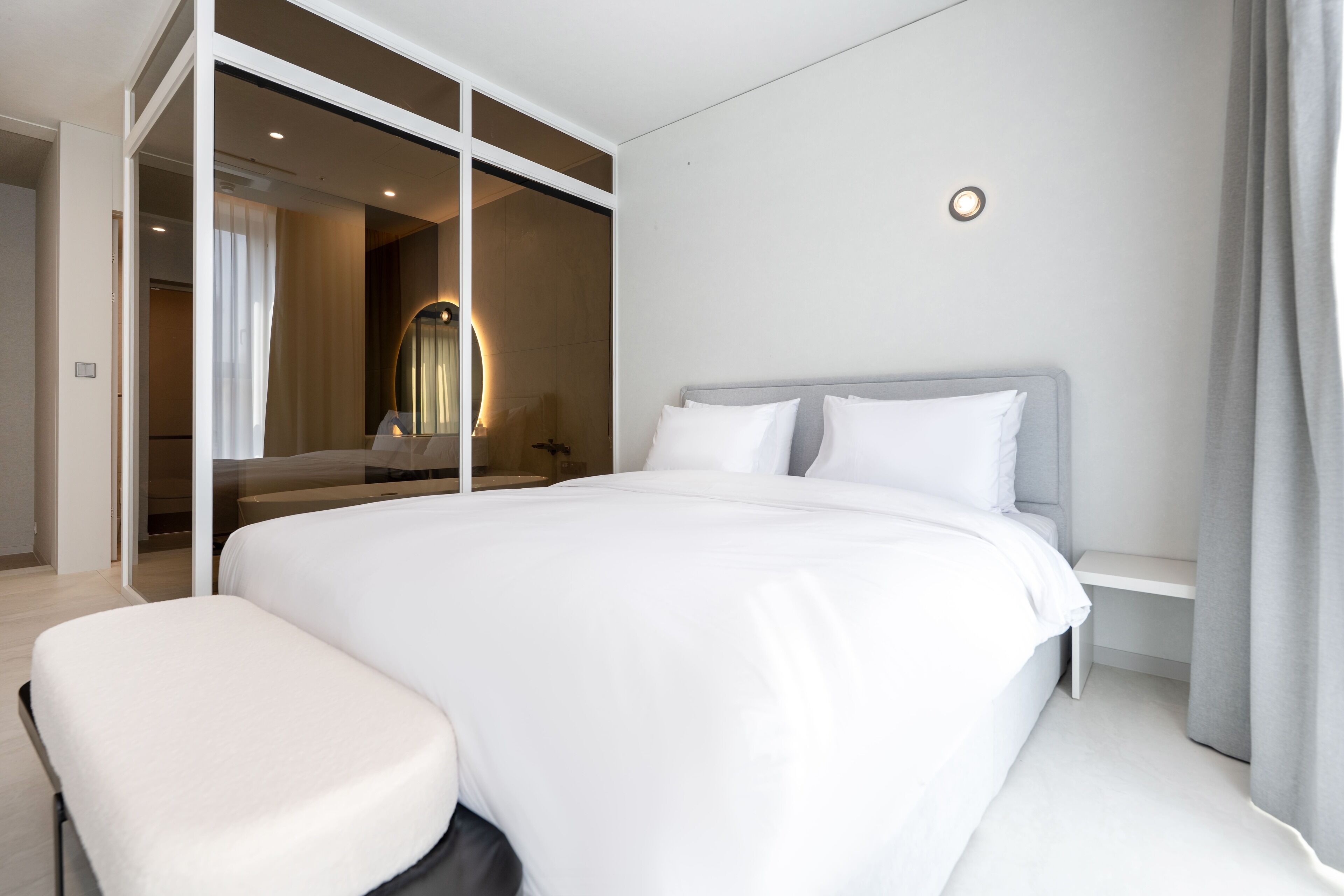 A modern hotel room with a large bed, a bedside table, and a seating area.
