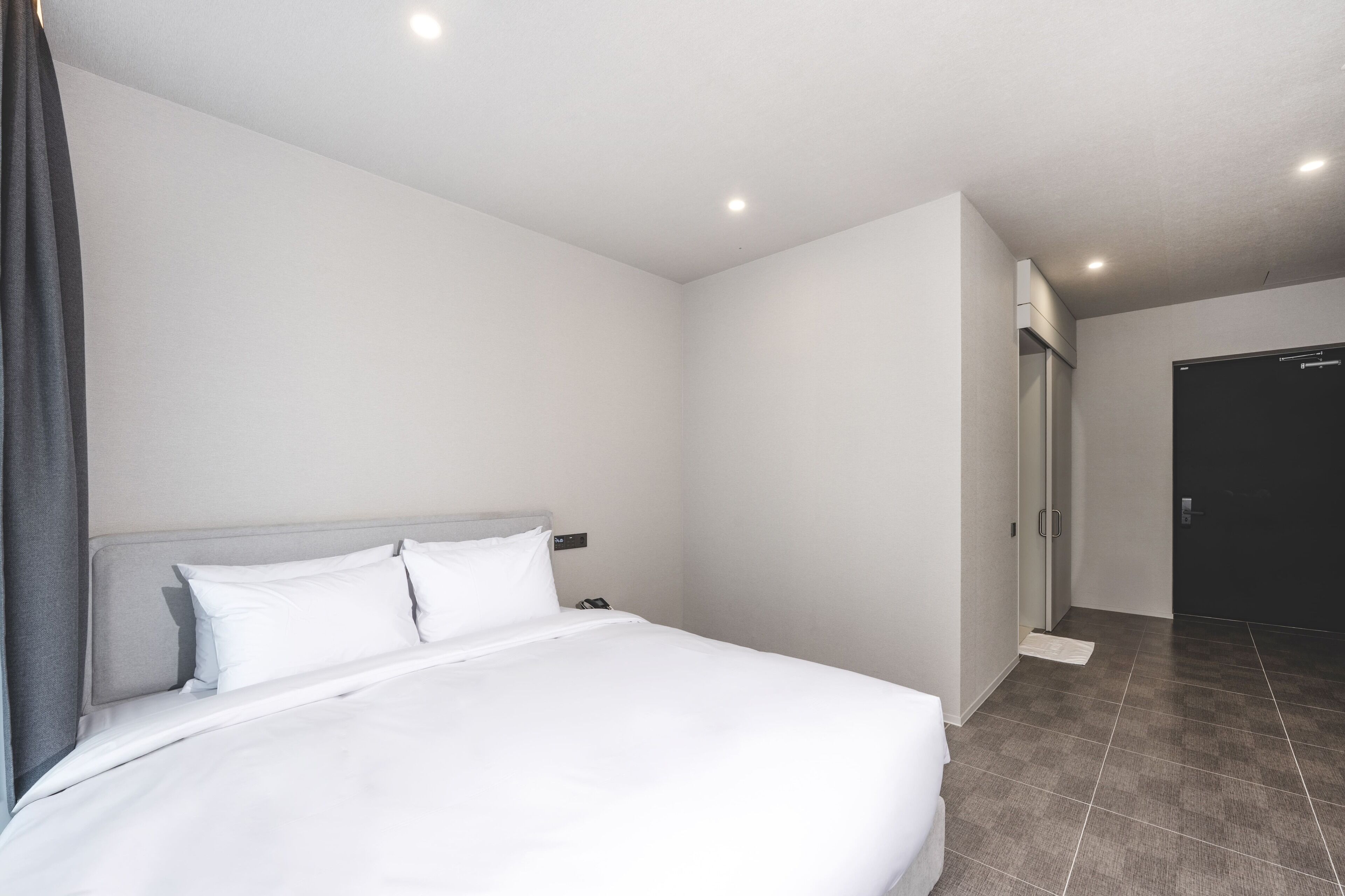 A hotel room with a large bed, a wardrobe, and a door.