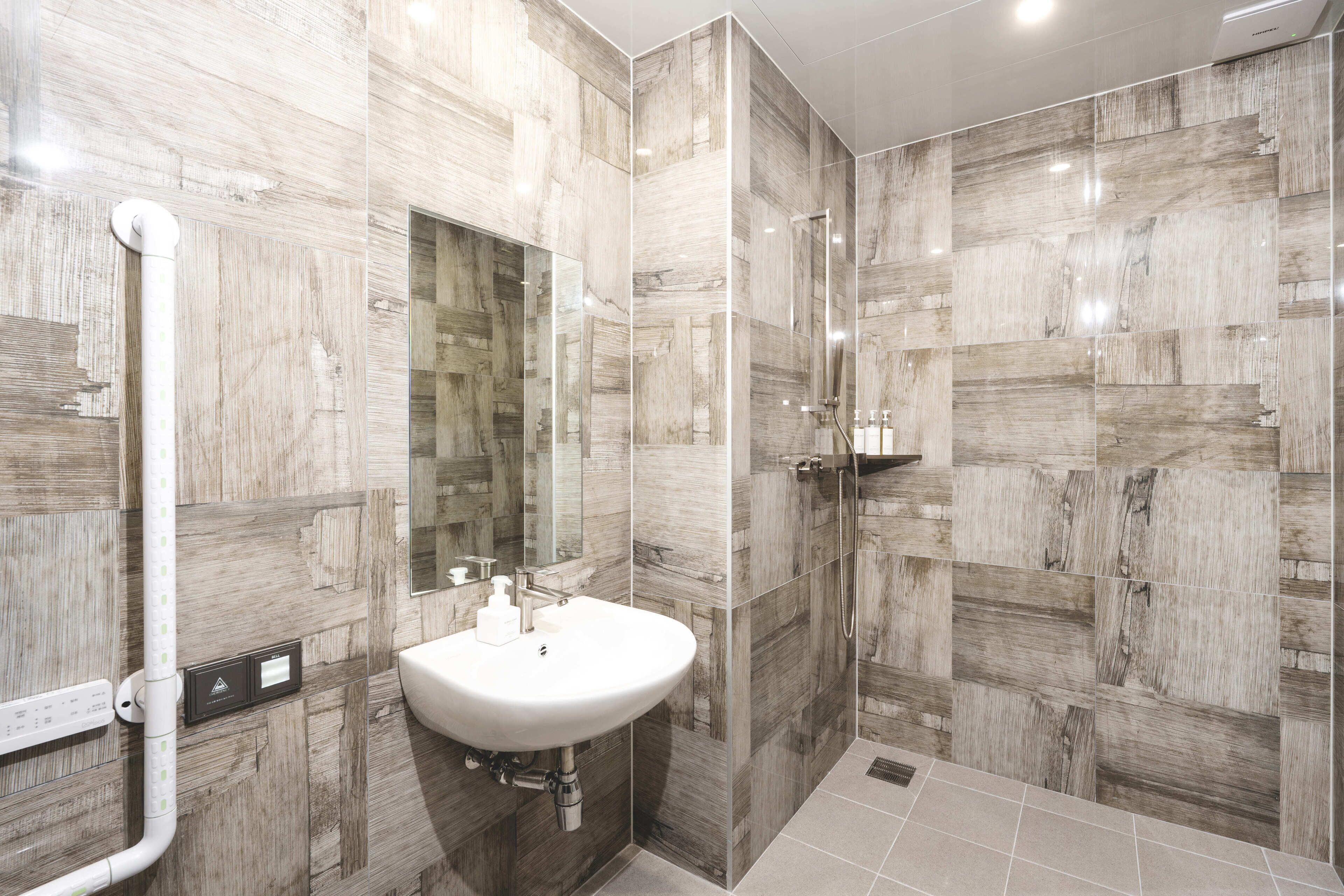 A modern bathroom with a white sink, a mirror, and a shower area.