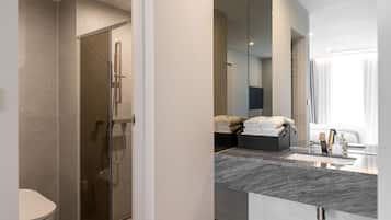 Un baño moderno con cabina de ducha de vidrio, lavamanos de mármol y un espejo grande.
