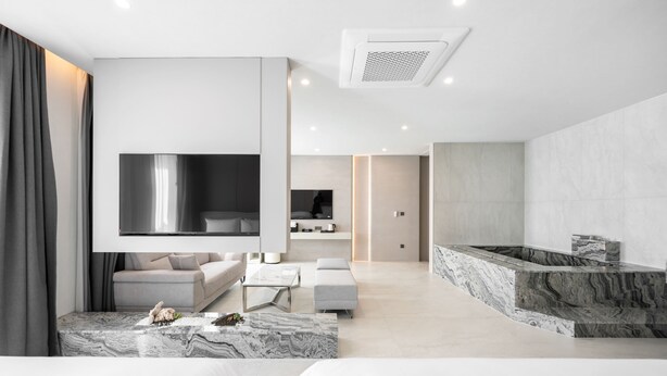 A modern living room with a large TV, a sofa, a coffee table, and a marble accent wall. - Gyeongju city hotel (Gyeongju)