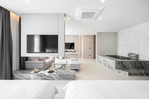 Ein modernes Wohnzimmer mit großem Fernseher, einer Couch, einem Couchtisch und einer Wand mit Marmorverkleidung.