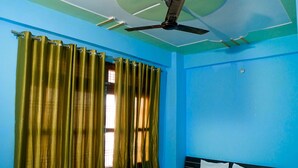 A bedroom with a bed, curtains, and a ceiling fan. - Hotel Meraki Inn (Lucknow)