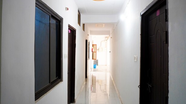 A hallway with white walls, a marble floor, and doors on both sides. - Hotel Meraki Inn (Lucknow)
