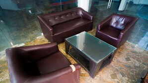 A seating area with a glass-top table and leather chairs. - Hotel Meraki Inn (Lucknow)