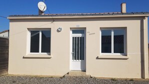 Un bâtiment à deux étages, doté d’une façade beige, d’une antenne parabolique sur le toit et d’un petit jardin agrémenté de gravier.