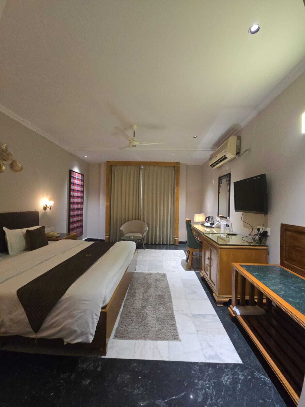 A hotel room with a bed, desk, chair, and a television.