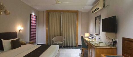 A hotel room with a bed, desk, chair, and a television.