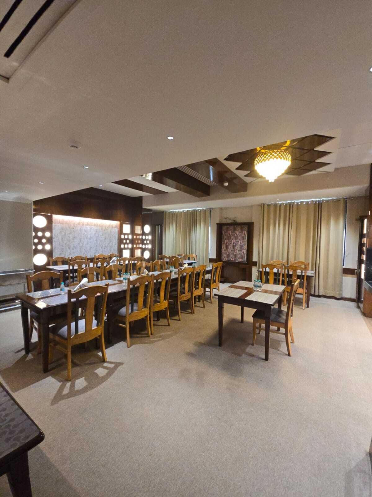 A conference room with multiple tables and chairs, a patterned wall, and a chandelier.