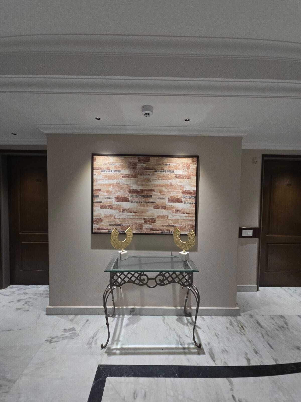A lobby with a glass table, two golden horseshoe-shaped objects, and a brick-patterned wall.