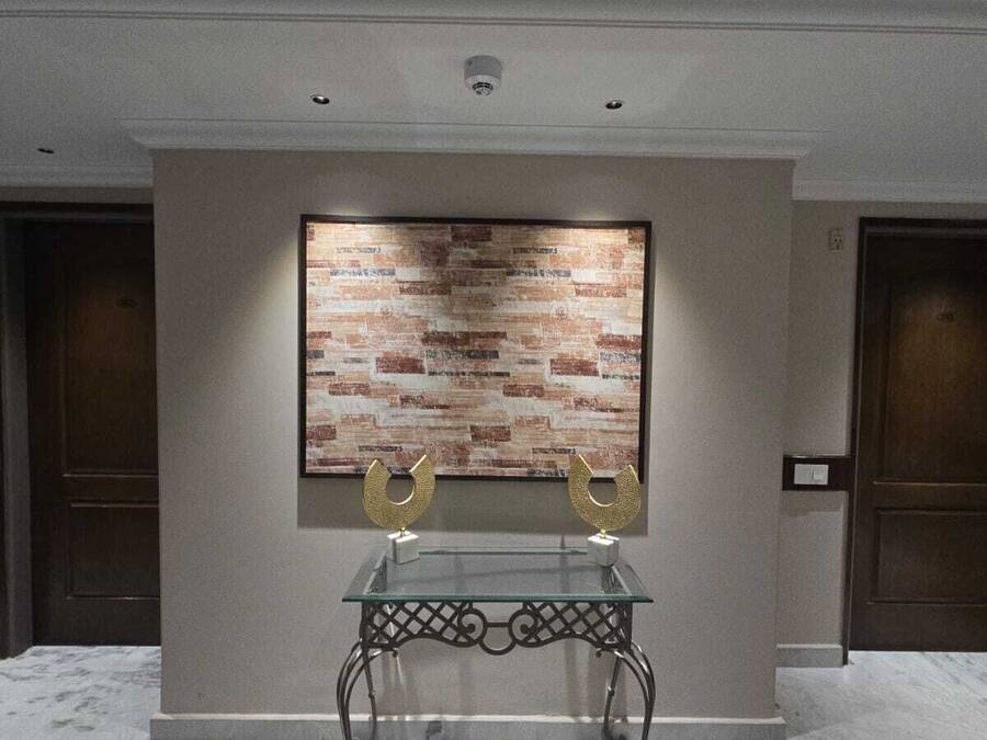 A lobby with a glass table, two golden horseshoe-shaped objects, and a brick-patterned wall.