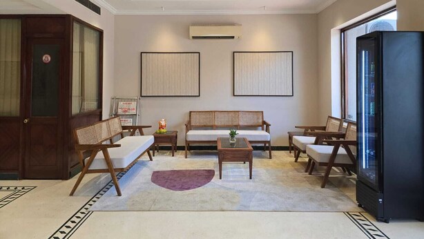 A living room with a sofa, two armchairs, a coffee table, a chandelier, and a large black refrigerator. - Hotel Supreme Suites Ludhiana  (Ludhiana)
