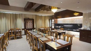 A conference room with long tables and chairs, a kitchen area, and a large screen. - Hotel Supreme Suites Ludhiana  (Ludhiana)
