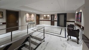 A spacious lobby with marble flooring, a staircase, a reception desk, and a fire extinguisher. - Hotel Supreme Suites Ludhiana  (Ludhiana)