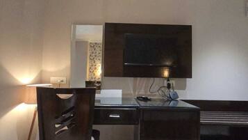 Una habitación moderna con una televisión de pantalla plana montada en la pared, un escritorio con una silla y un cesto de basura.