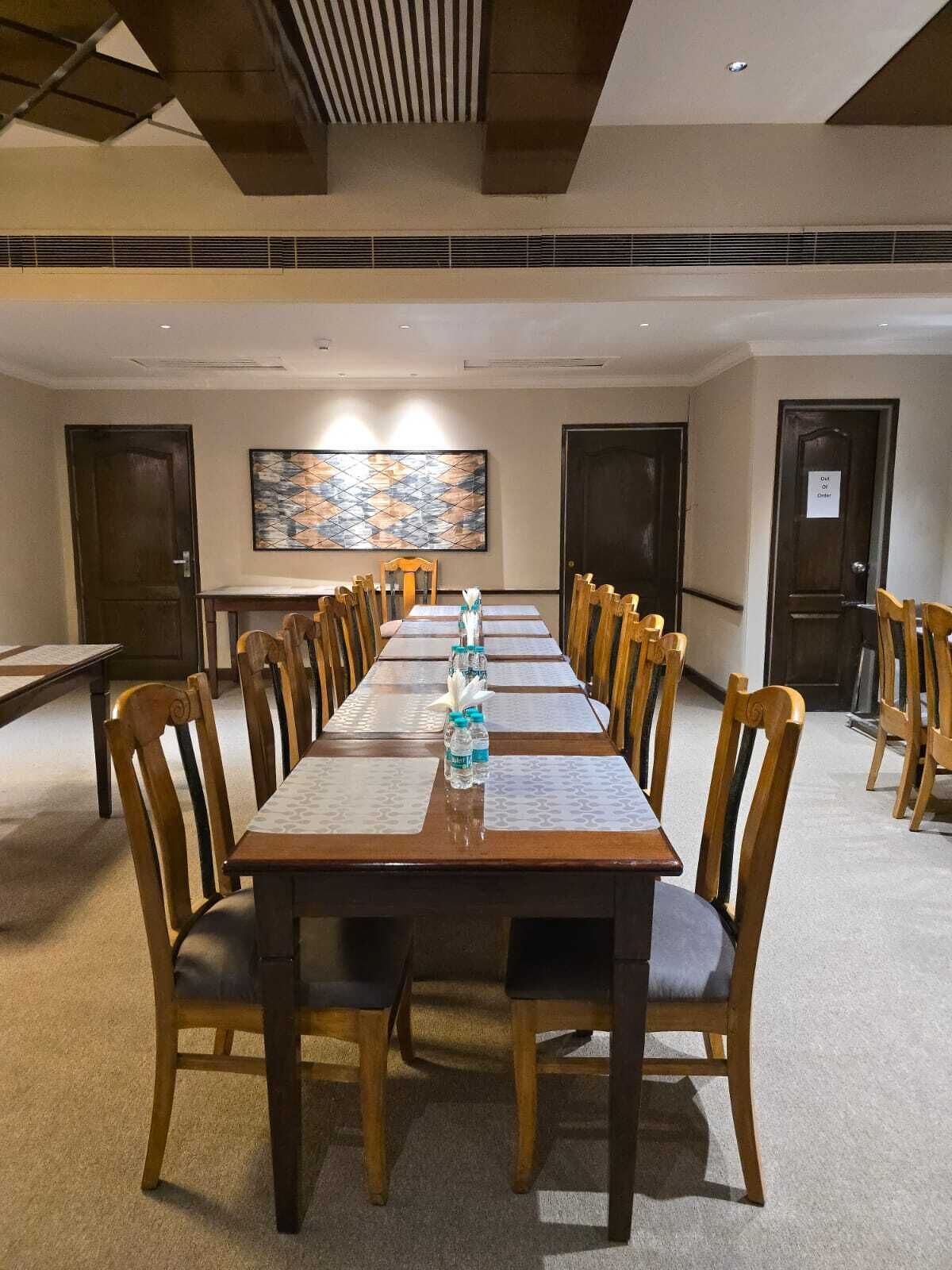 Un salón de conferencias con una larga mesa, sillas de madera y un cuadro abstracto grande en la pared.