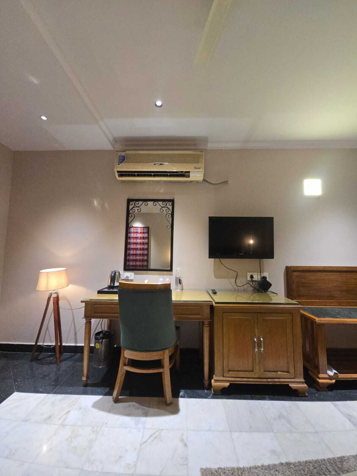Una habitación de hotel con escritorio, silla, televisor y aire acondicionado.