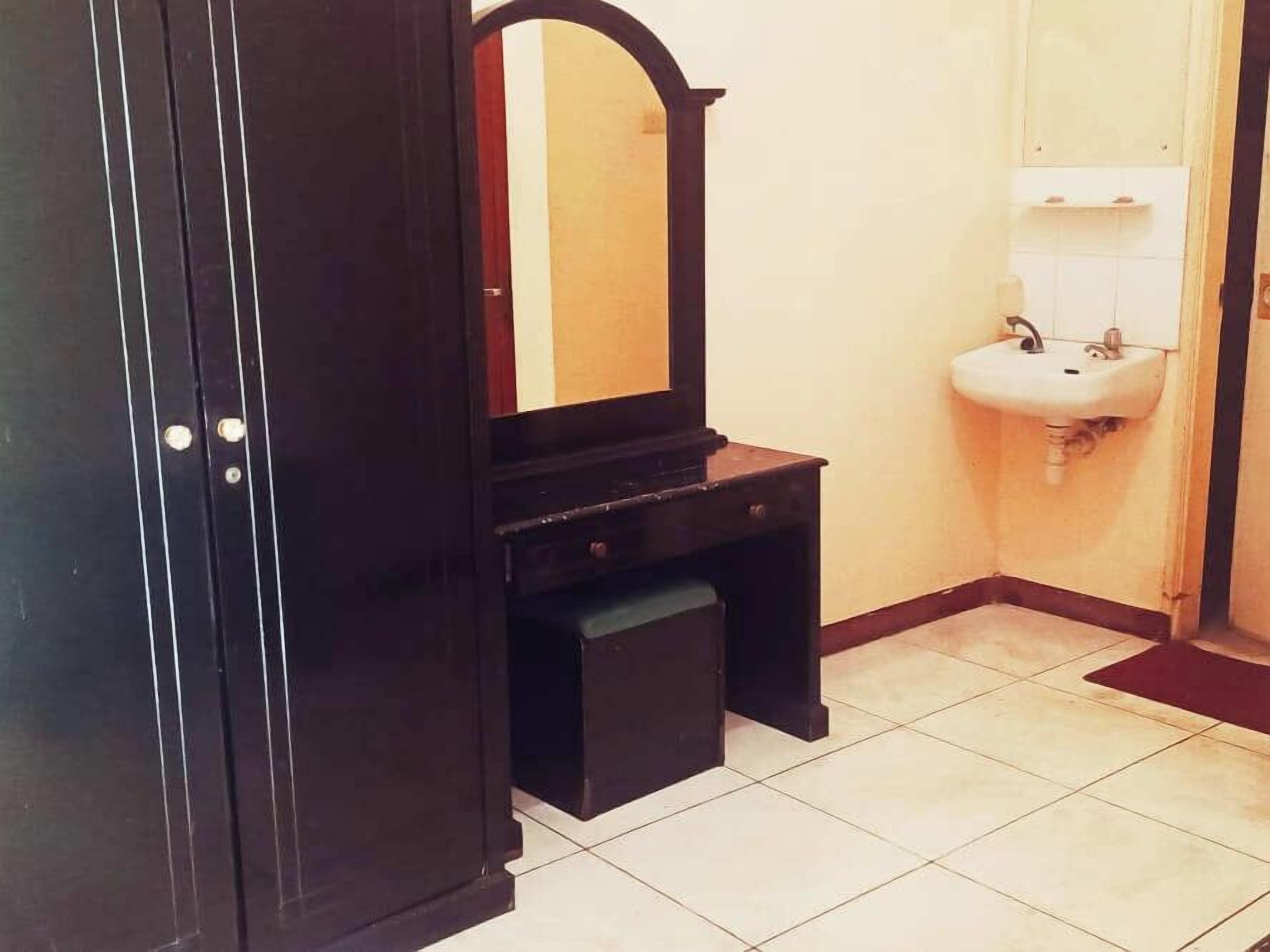 A bathroom with a dark wooden vanity, a mirror, and a white sink.