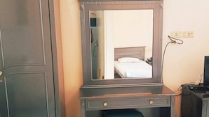Ein Zimmer mit großem Spiegel, einem Bett, einem Schreibtisch und einem kleinen Hocker.