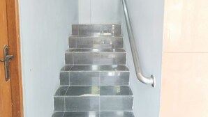 Un escalier avec une rampe, une porte et un mur muni d’un interrupteur.