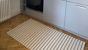 Una cocina moderna con gabinetes grises, horno empotrado, pileta de acero inoxidable y un protector contra salpicaduras de madera.