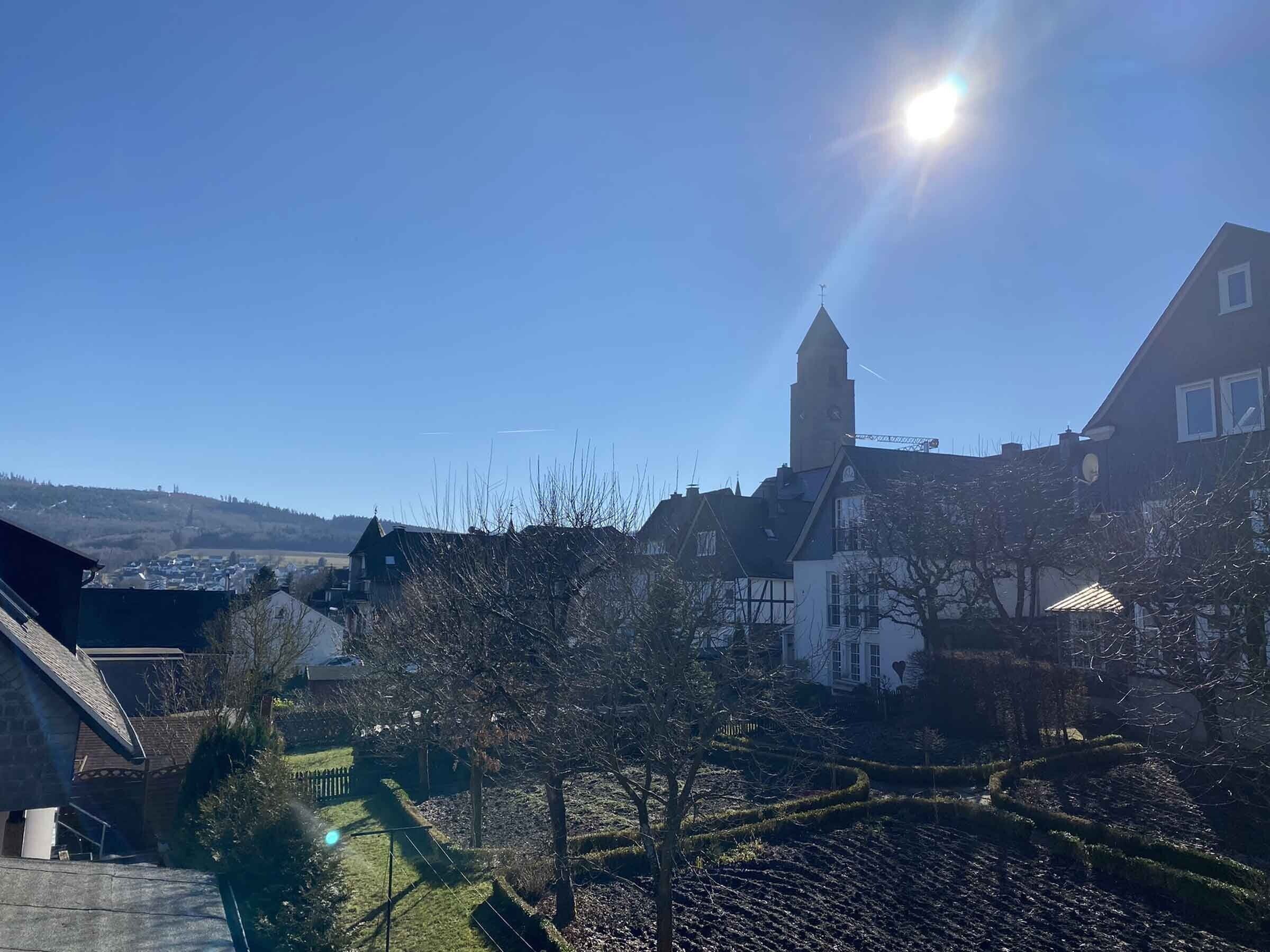 Ein Wohngebiet mit einem markanten Kirchturm, blauem Himmel und weiter Aussicht auf eine Stadt.