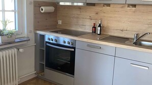 Una cocina moderna con horno empotrado, pileta de acero inoxidable y muebles de madera.