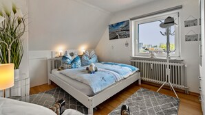 Una camera da letto con un letto, una finestra, un termosifone, una lampada e una pianta.