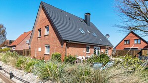 Una casa in mattoni con tetto spiovente, un'antenna parabolica e un giardino con erba alta.