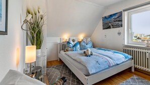 A bedroom with a bed, bedside lamps, a window, and a radiator. - Apartment 'Wattlöwe Tönning' with Private Terrace, Private Garden and Wi-Fi (Tönning)