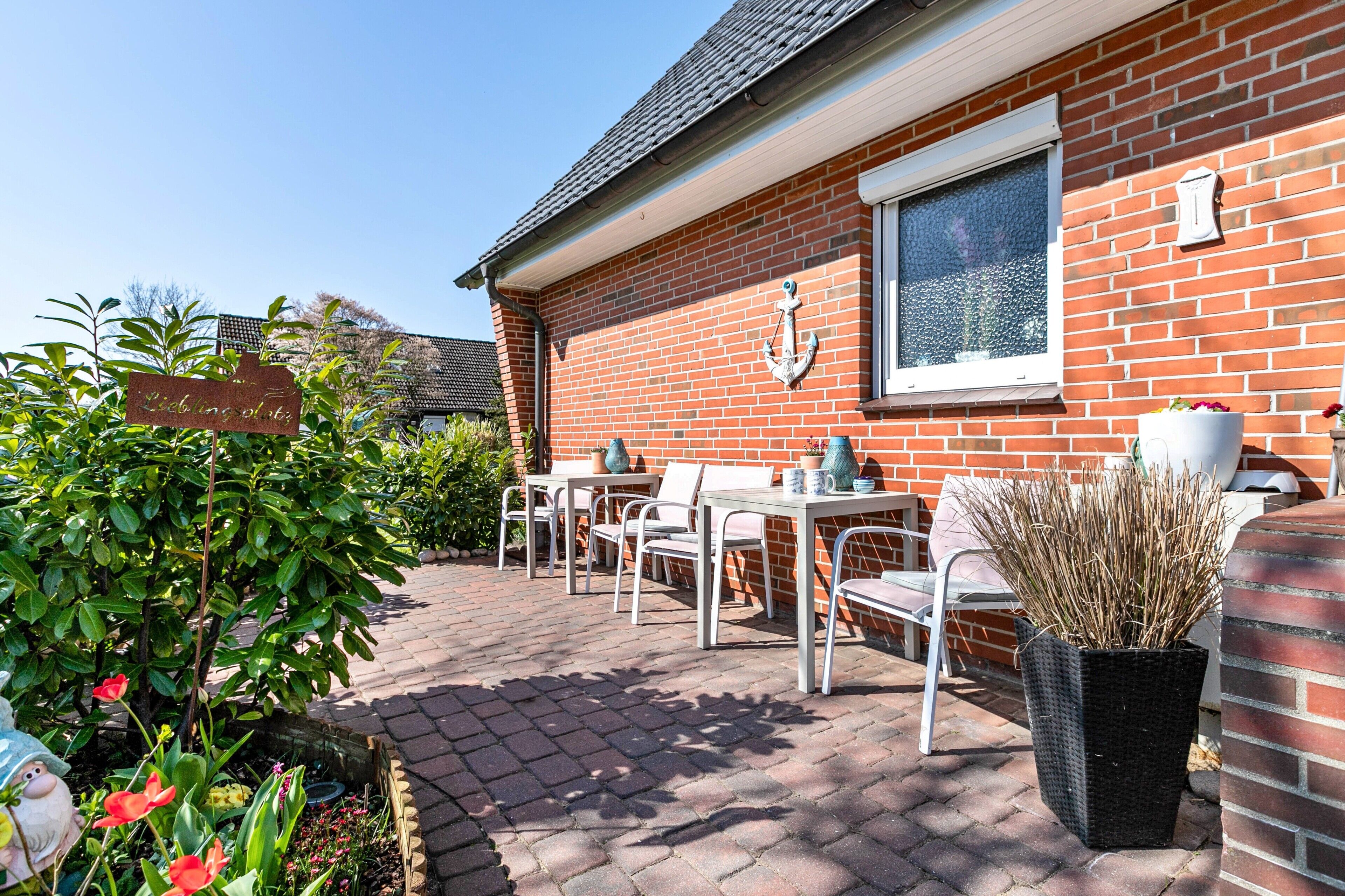 A patio area with a brick wall, a window, outdoor furniture, and a sign.