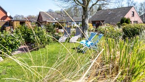 A residential area with houses, a tree, and a lawn with two lounge chairs. - Apartment 'Wattlöwe Tönning' with Private Terrace, Private Garden and Wi-Fi (Tönning)