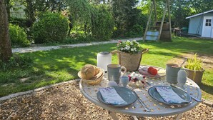 A round table with plates, a basket of bread, a pitcher, a mug, and a flower pot. - Studio Apartment 'Villa Gute Zeit - Cosy  Apart' with Shared Terrace, Shared Garden and Wi-Fi (Nortorf)