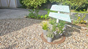 A signpost with 'Cosy Apartment' written on it, surrounded by gravel and potted plants. - Studio Apartment 'Villa Gute Zeit - Cosy  Apart' with Shared Terrace, Shared Garden and Wi-Fi (Nortorf)
