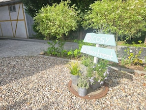 Un cartel con la leyenda 'Cosy Apartment', rodeado de grava y plantas en macetas.