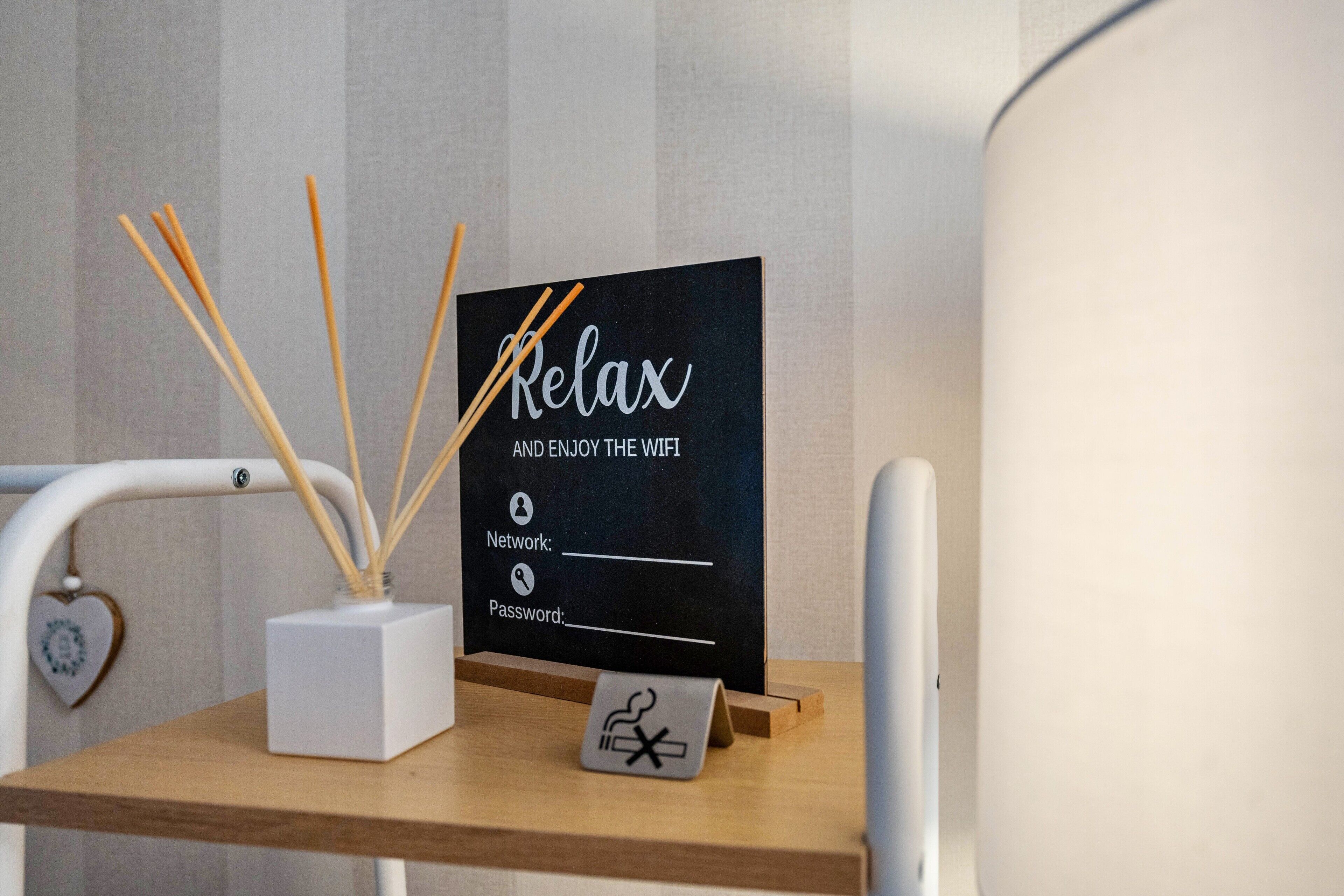 Et skrivebord med et skilt, der står 'Slap af og nyd WiFi', en hvid kasse med rørrebensstænger, og en hjerteformet pynt.