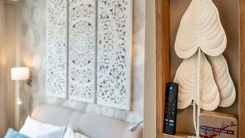 Une chambre moderne avec un canapé, un panneau mural décoratif, une télécommande et un objet décoratif en forme de feuille.