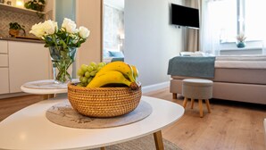 A living room with a round table, a sofa, a television, and a window. - Studio Apartment 'Villa Gute Zeit - Cosy  Apart' with Shared Terrace, Shared Garden and Wi-Fi (Nortorf)