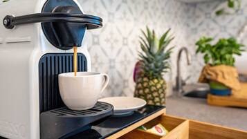 Een koffiemachine met een kop, een ananas en een houten dienblad met spullen.