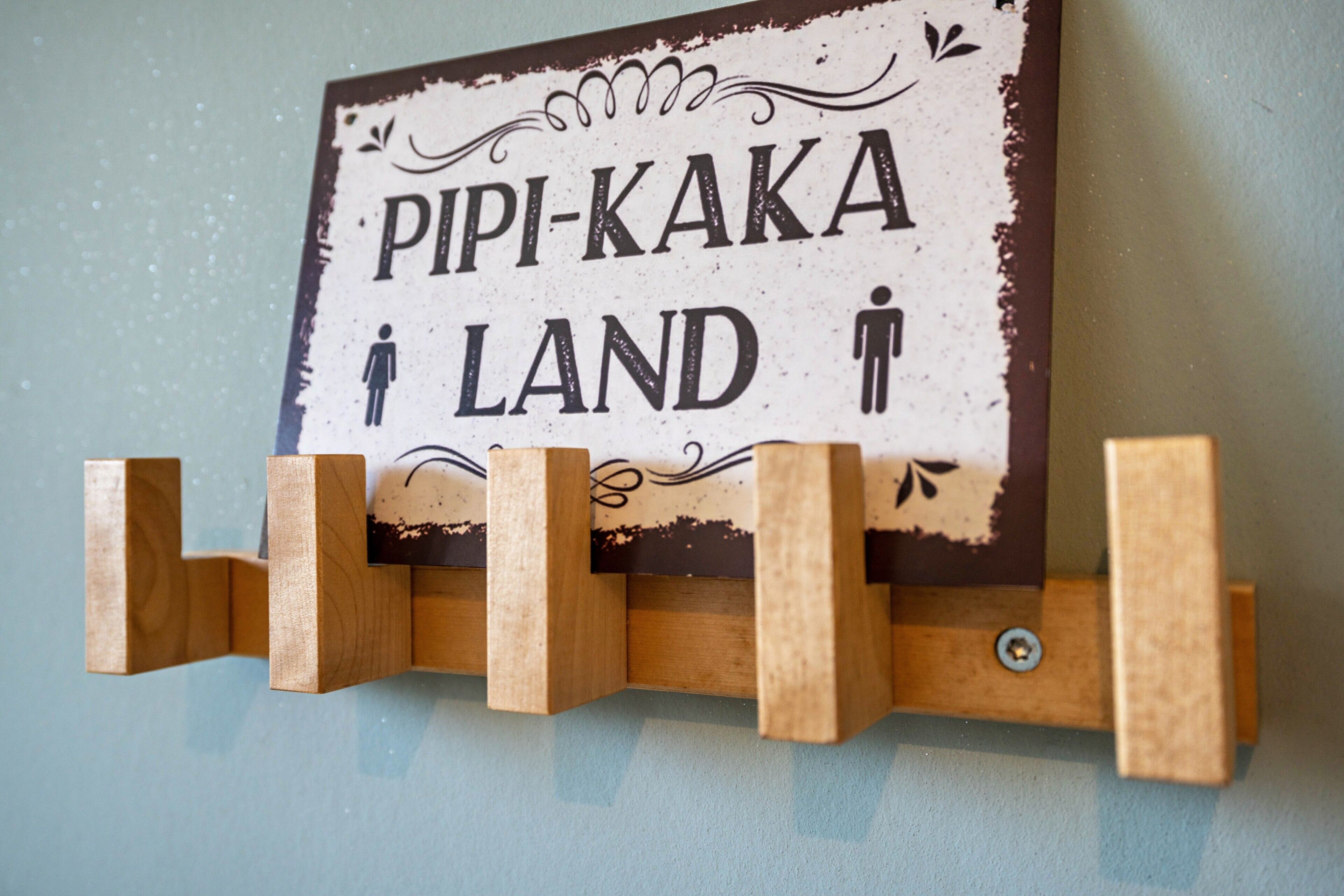 En skylt med texten ”PIPI-KAKA LAND” och symboler som föreställer en man och en kvinna.