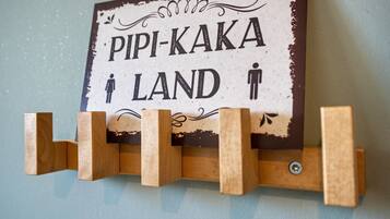 En skylt med texten ”PIPI-KAKA LAND” och symboler som föreställer en man och en kvinna.