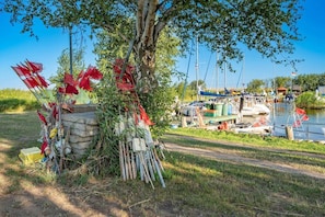 Een boom met rode vlaggen, een steiger met boten en een heldere lucht.