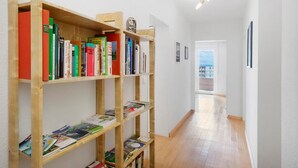 A hallway with wooden bookshelves filled with books, a wooden floor, and a door leading to a balcony. - Holiday Apartment 'Bodenseewohnung Bär' with Lake View, Balcony, and Wi-Fi (Immenstaad am Bodensee)