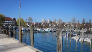 A marina with boats docked, a clear sky, and buildings in the background. - Holiday Apartment 'Bodenseewohnung Bär' with Lake View, Balcony, and Wi-Fi (Immenstaad am Bodensee)