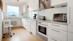 A modern kitchen with white cabinetry, a built-in oven, a toaster, and a dishwasher. - Holiday Apartment 'Bodenseewohnung Bär' with Lake View, Balcony, and Wi-Fi (Immenstaad am Bodensee)