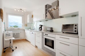 A modern kitchen with white cabinetry, a built-in oven, a toaster, and a dishwasher.