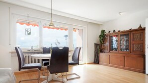A dining area with a round table, four chairs, and a view of the outdoors through large windows. - Holiday Apartment 'Bodenseewohnung Bär' with Lake View, Balcony, and Wi-Fi (Immenstaad am Bodensee)