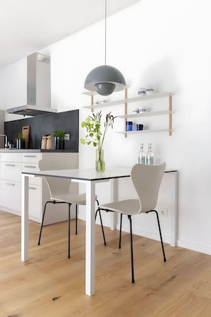 A modern kitchen with white cabinetry, a black pendant light, and a vase with green plants.