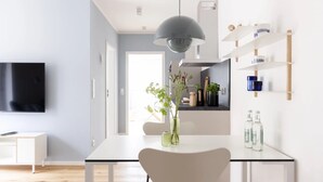 A modern kitchen with a dining table, a TV mounted on the wall, and a pendant light. - Apartment 'Steuerbord' with Balcony and Wi-Fi (Sankt Peter-Ording)